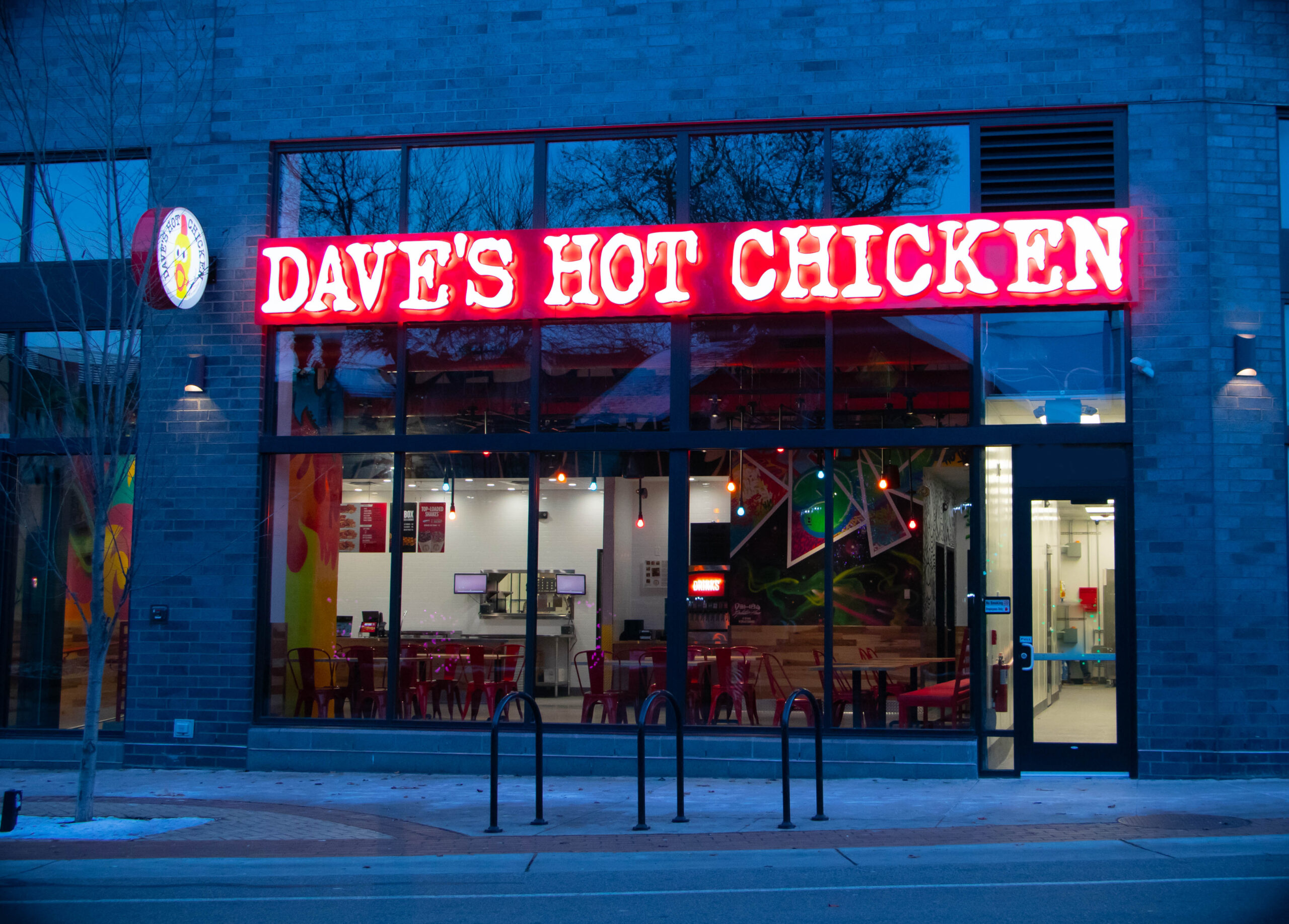 Exterior shot of the Dave's Hot Chicken signage lit up in neon lights in East Lansing MI